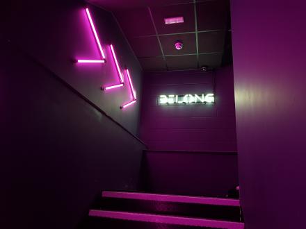 Belong gaming arena entrance with faux neon logo and arrows.